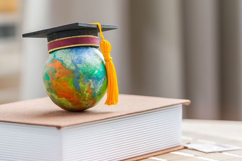 Small globe on a book with a graduation cap on top of the globe