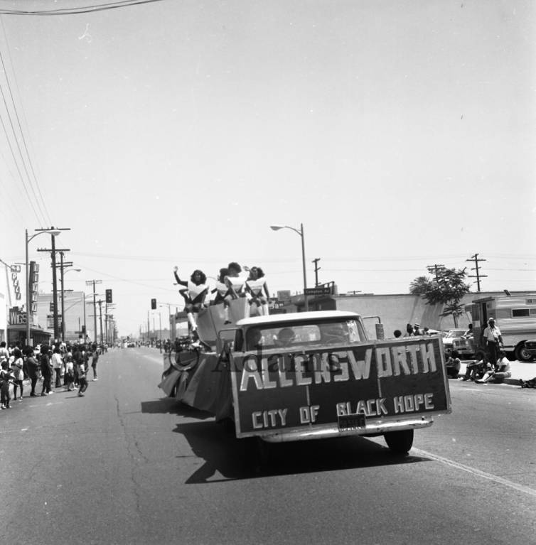 Women ride a float with a sign that says "Allensworth City of Black Hope"