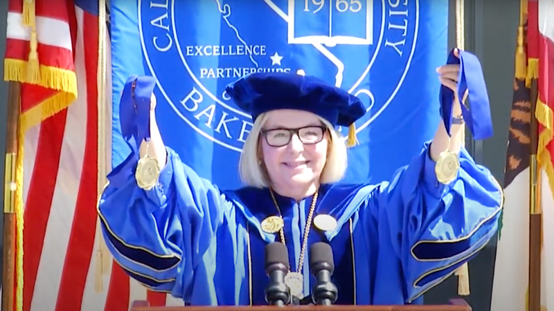 President Zelezny wearing a blue graduation gown and holding up two medals