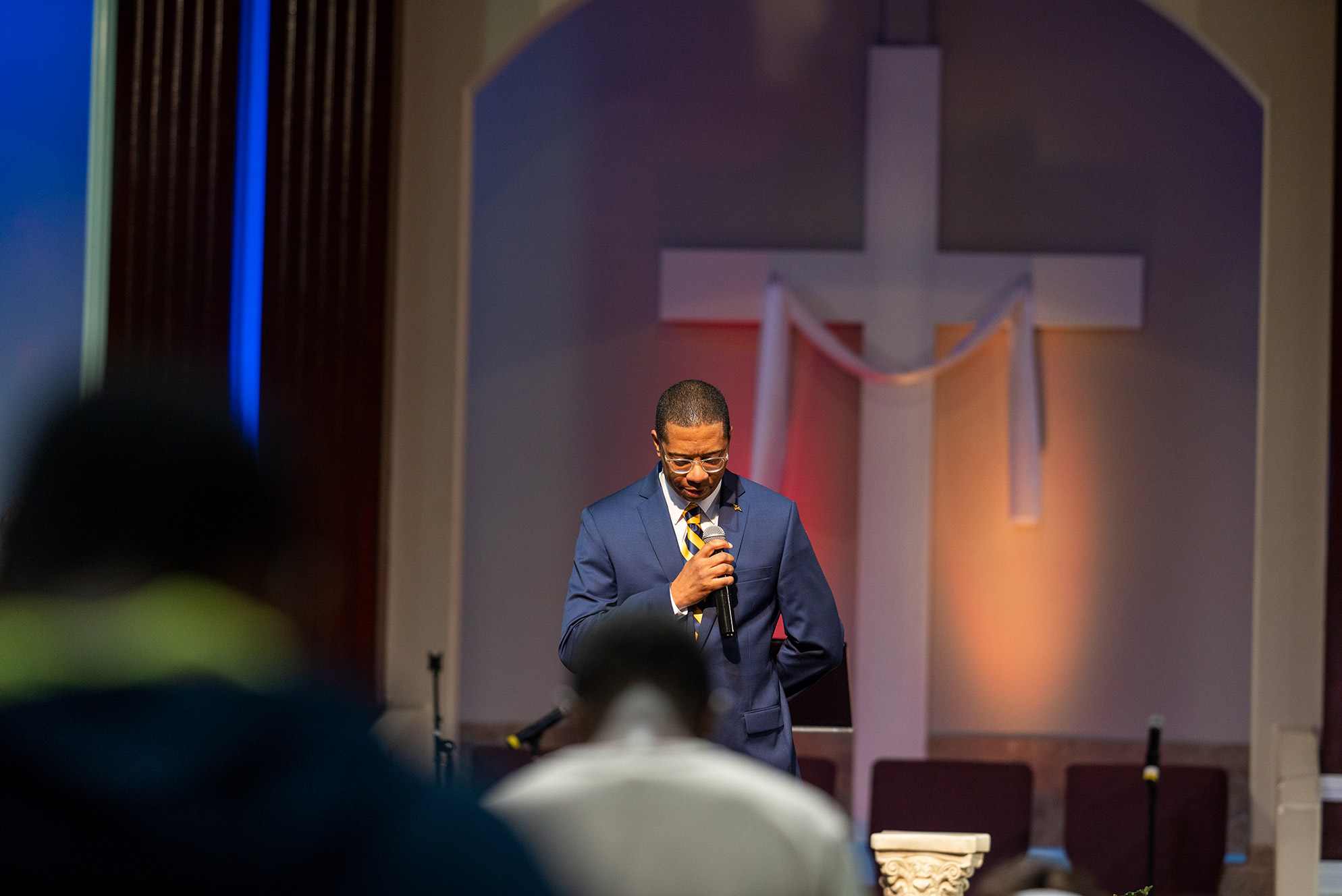 Pastor at church holding microphone and looking down at the floor
