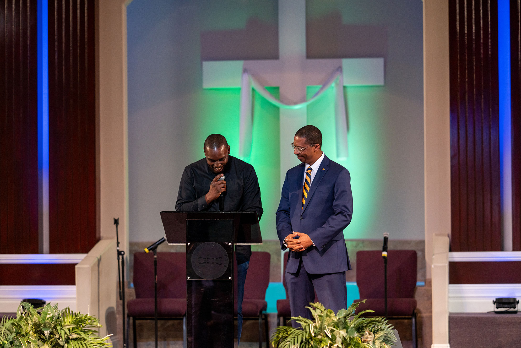 Two men on stage at church looking down at lectern
