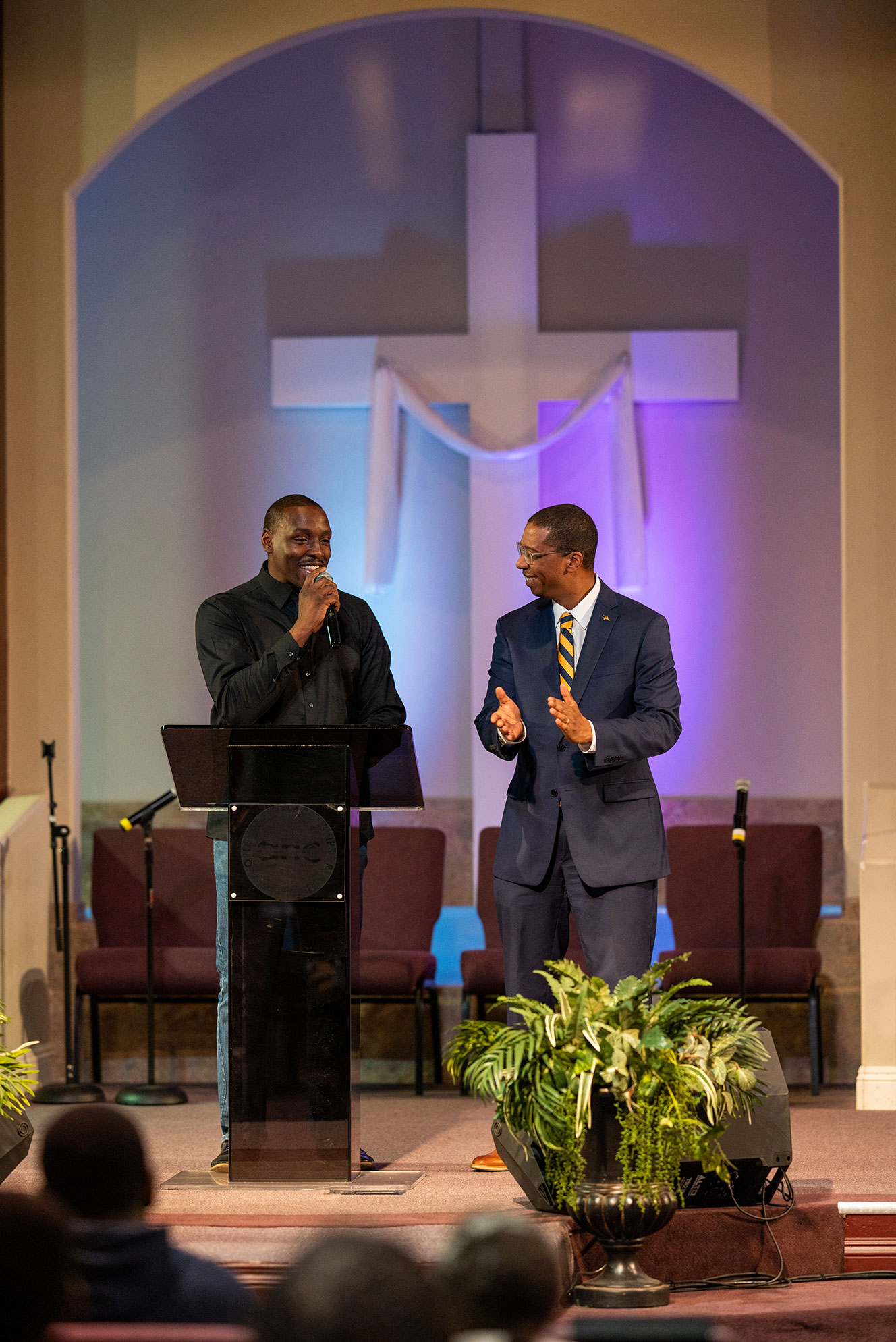 Two men on stage at church smiling at each other