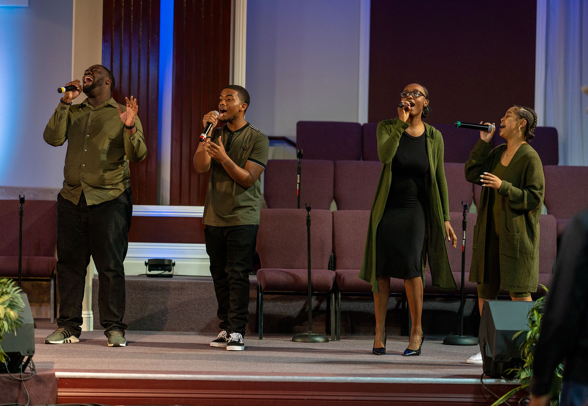 Four people on stage at church singing into microphones