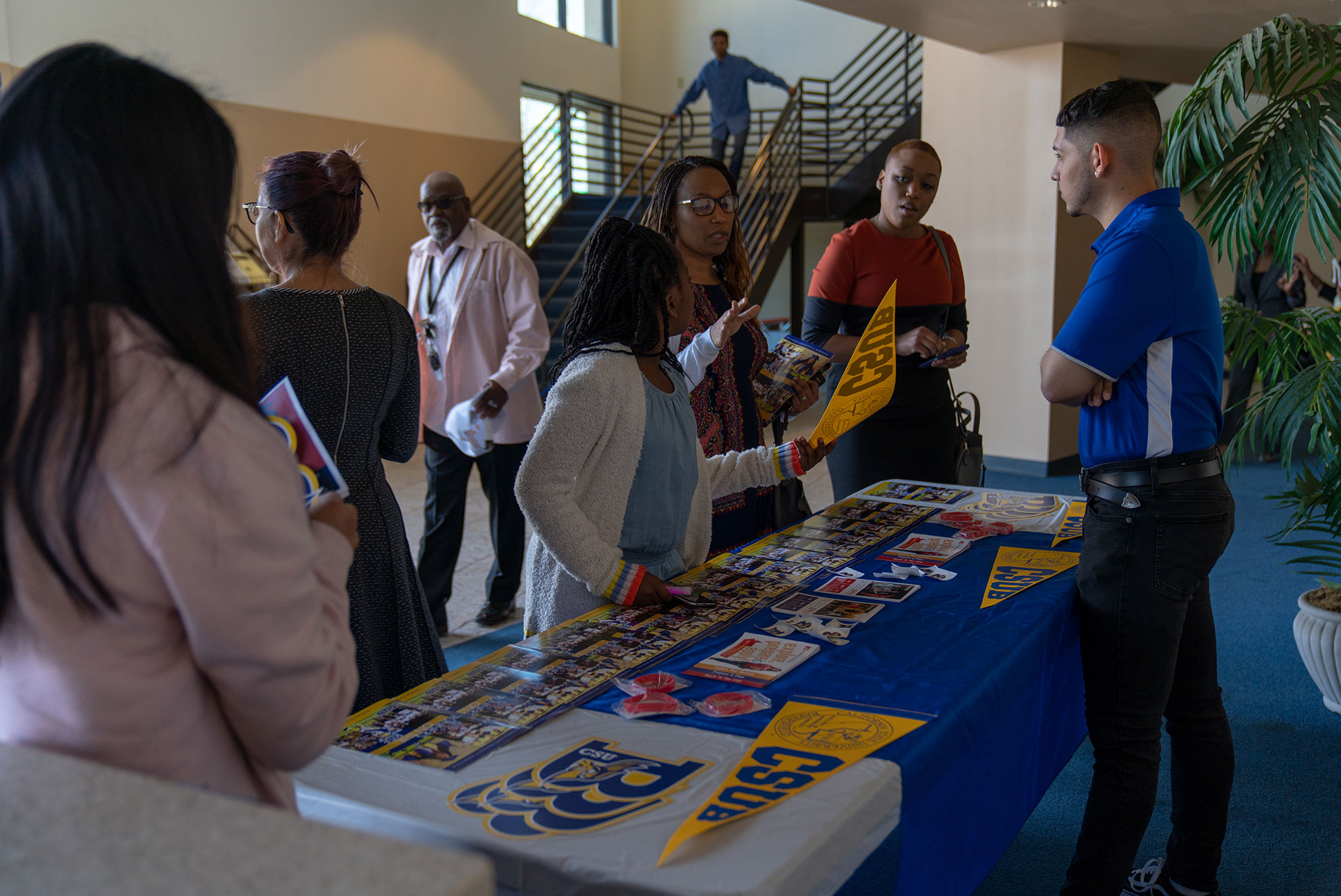 Merchandise table with CSUB swag and people talking to each other