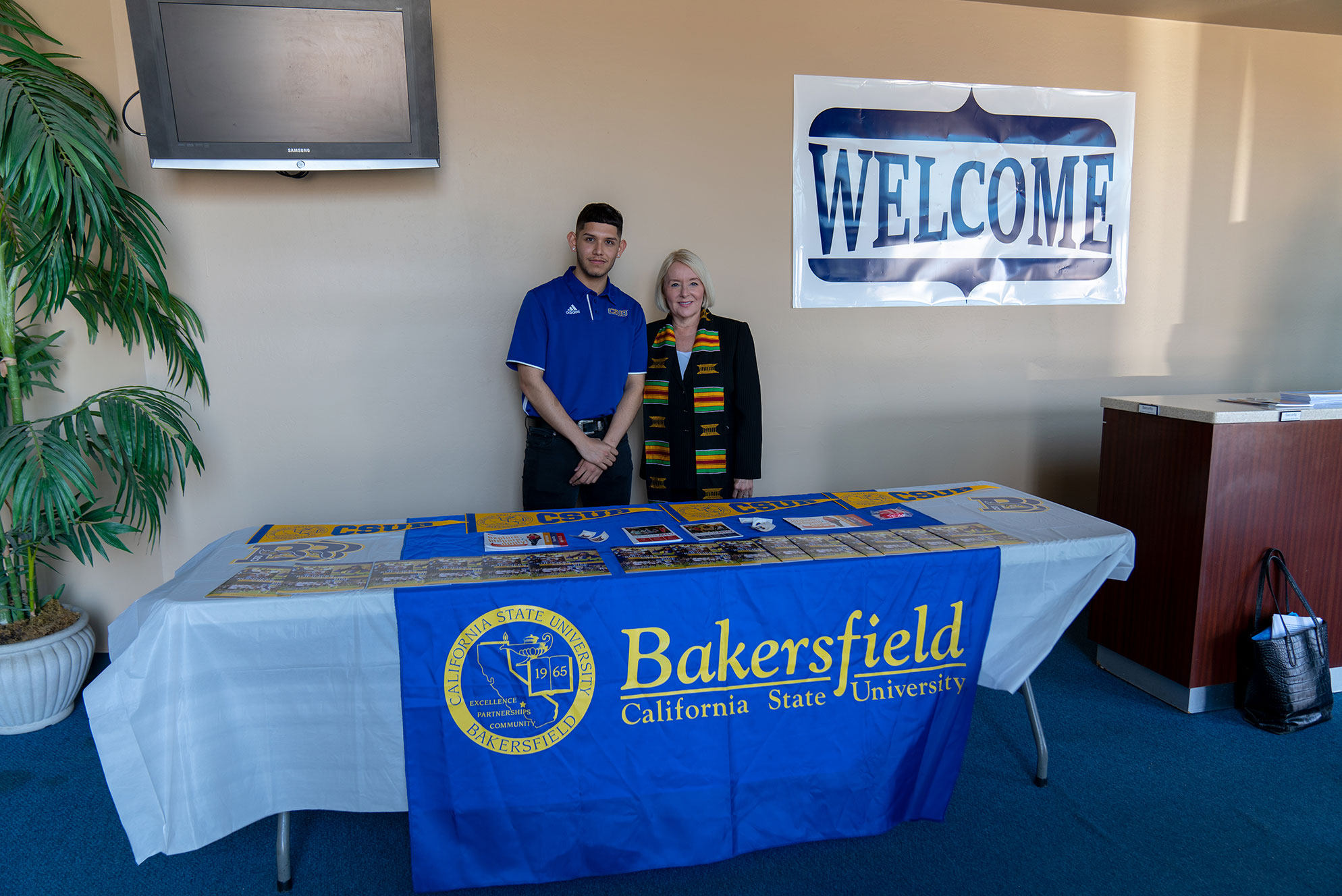 Man and woman standing behind a table that holds CSUB swag