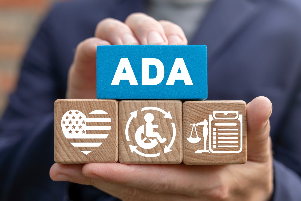 Person holding wooden cubes spelled "ADA" on them
