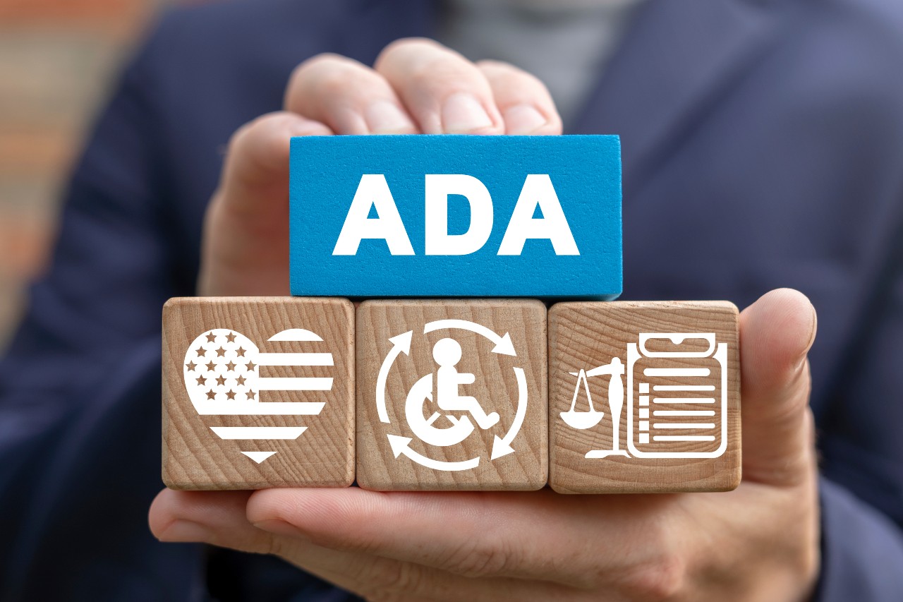 Person holding wooden cubes spelled ADA on them