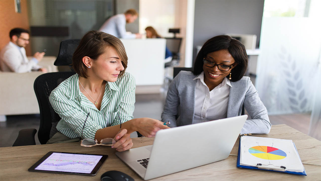 Two women looking at a laptop, talking