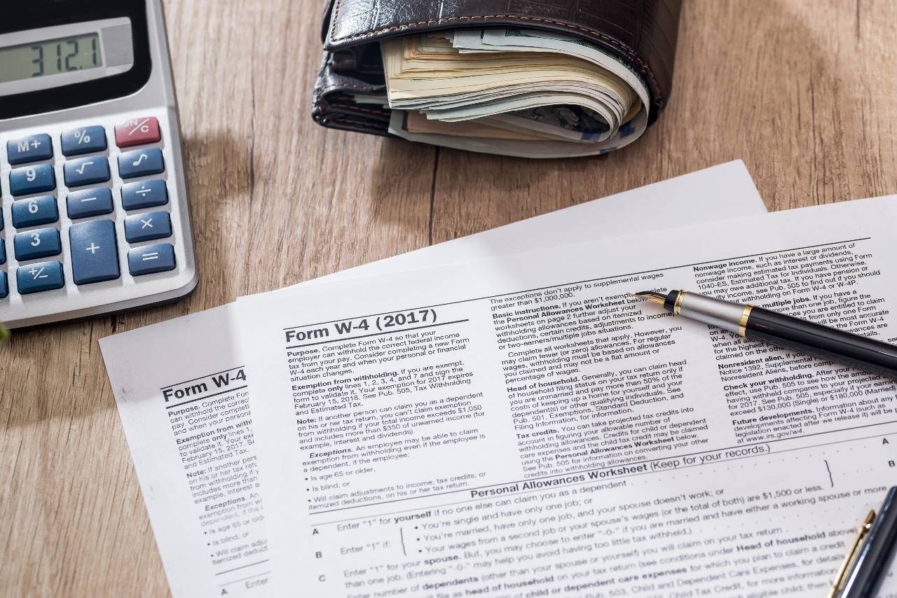 Tax paperwork, calculator, and pens on a desk