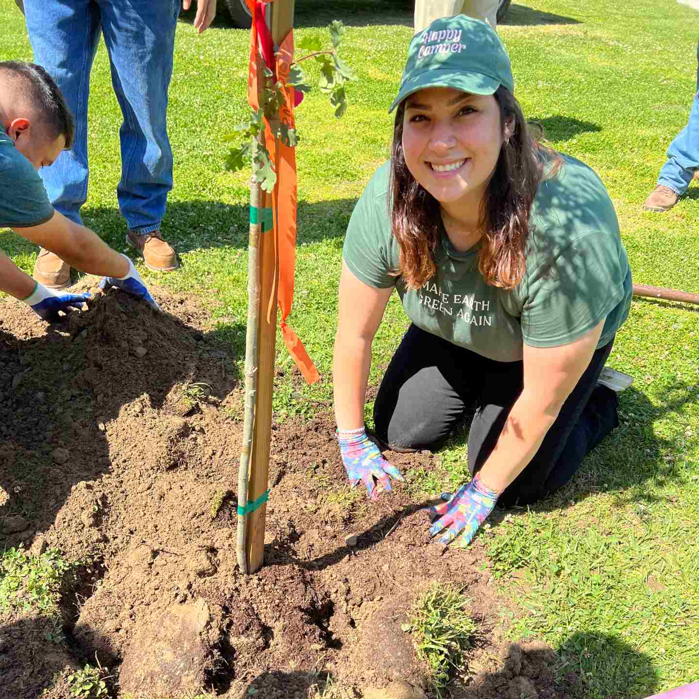 Girl on her knees planting a tree